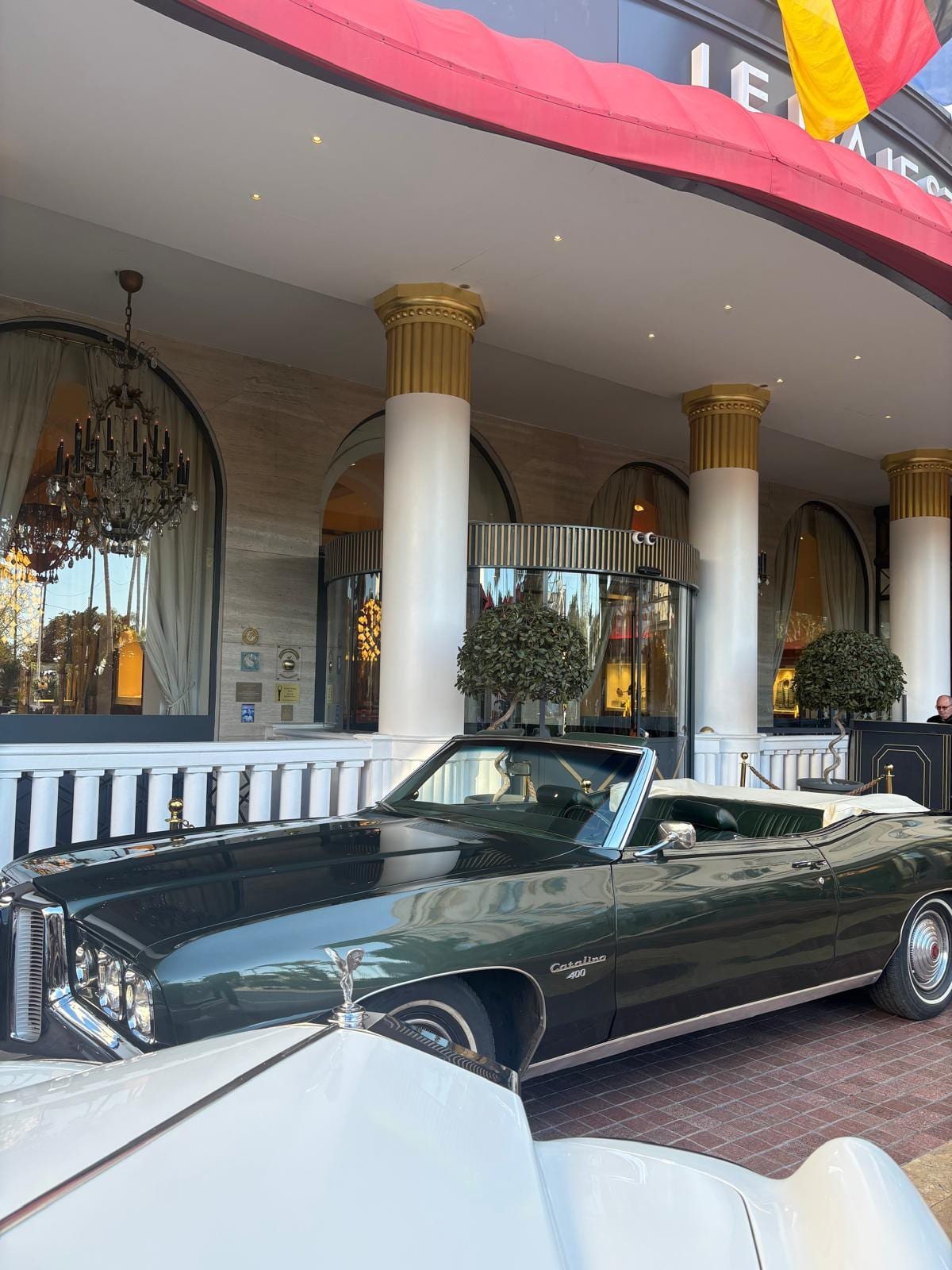 Vintage green Pontiac Catalina convertible parked outside a grand Cannes hotel entrance